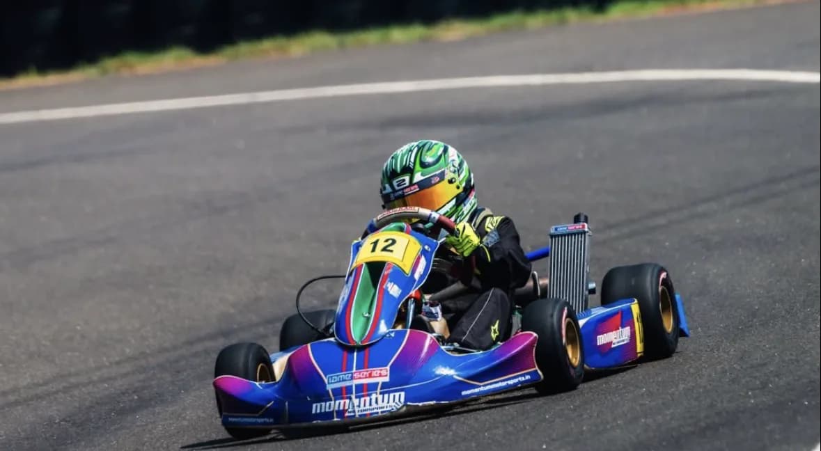 Vidyuth carries speed through a corner, green helmet down